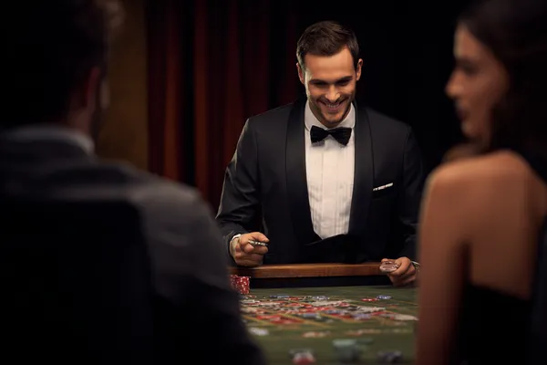 Lüks bir yeşil elbise giymiş bir kadın ve süslü bir rulet çarkı, MERIT CASINO’ün üst düzey casino atmosferini yansıtır.